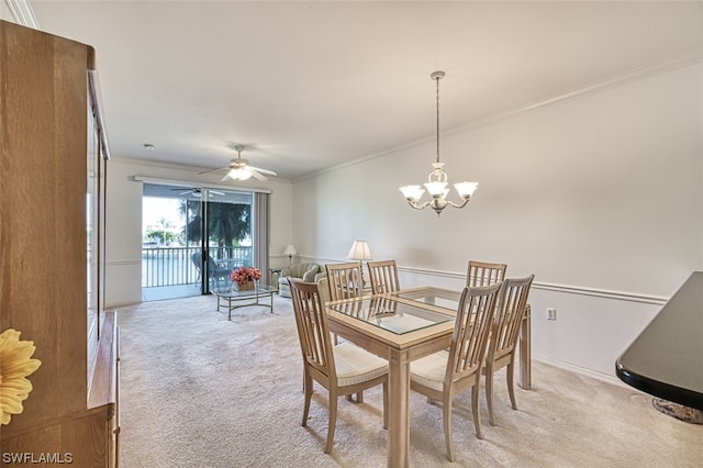 carpeted dining room with ceiling fan with notable chandelier and ornamental molding