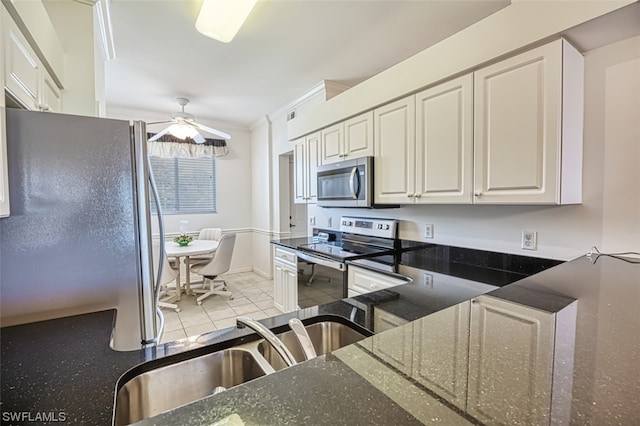 kitchen featuring stainless steel appliances, ceiling fan, light tile floors, and dark stone countertops