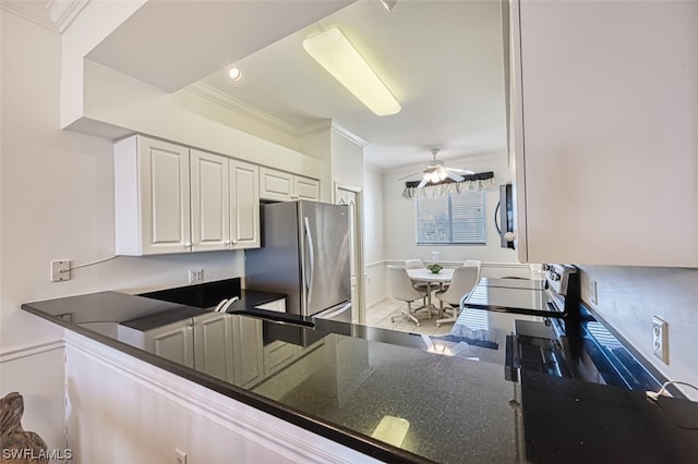 kitchen featuring ceiling fan, dark stone counters, crown molding, appliances with stainless steel finishes, and white cabinetry