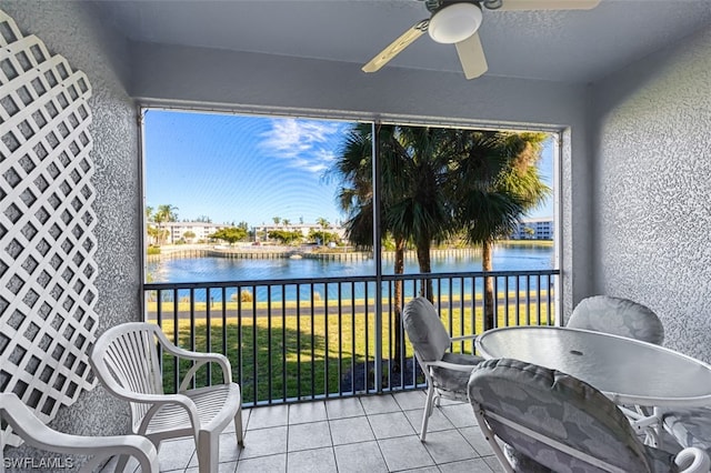 sunroom with ceiling fan and a water view