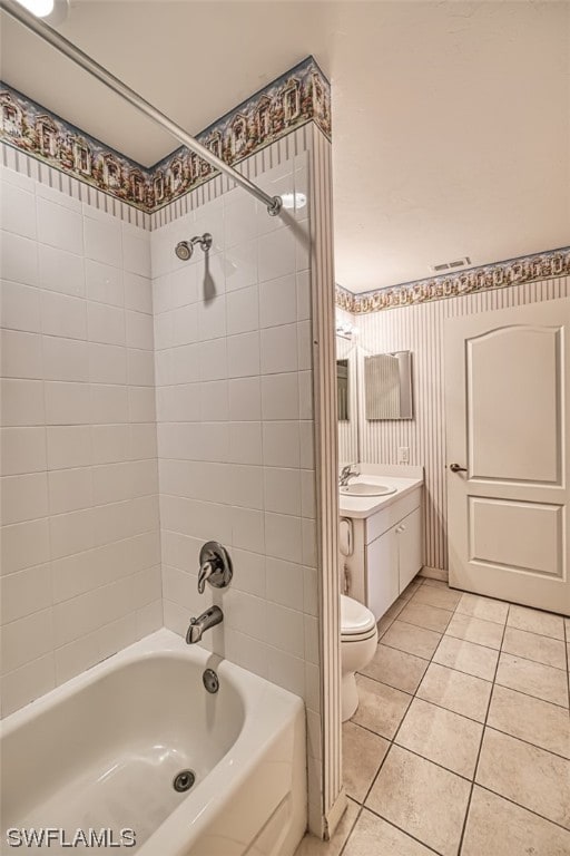 full bathroom with tiled shower / bath combo, tile floors, toilet, and vanity