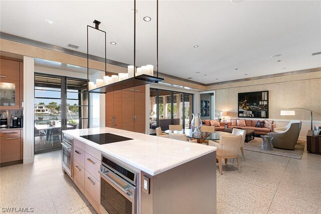 kitchen with a kitchen island, black electric stovetop, oven, and decorative light fixtures