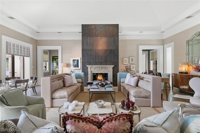 living room with high vaulted ceiling, a tray ceiling, ornamental molding, and a large fireplace