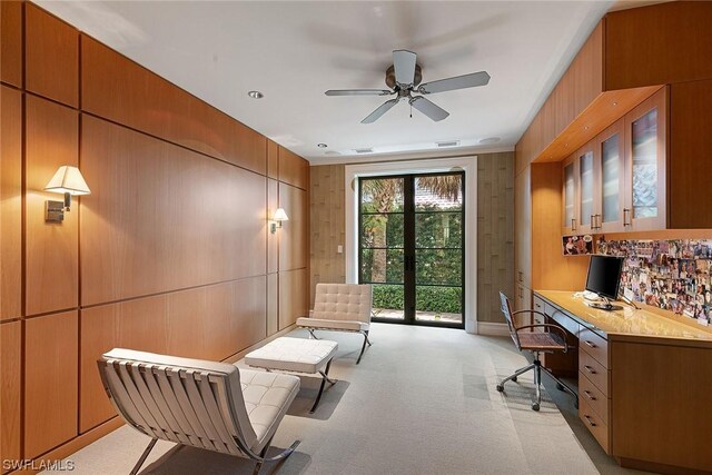 office area featuring built in desk, light colored carpet, and wood walls