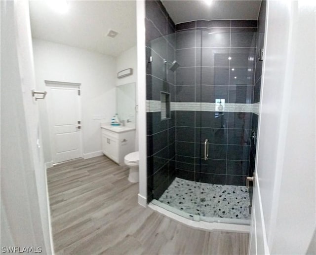 bathroom with vanity, a shower with shower door, hardwood / wood-style floors, and toilet