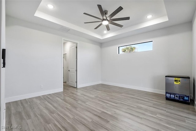 empty room with a raised ceiling and light hardwood / wood-style flooring