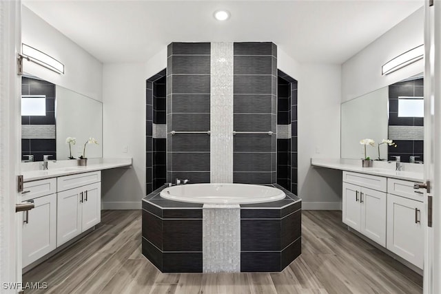 bathroom featuring vanity, hardwood / wood-style floors, and tiled bath