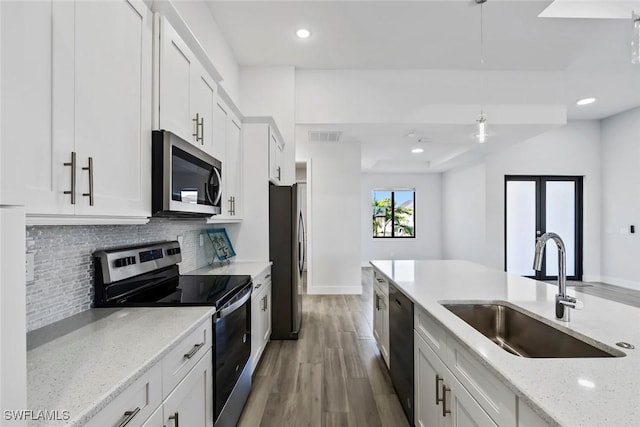 kitchen featuring sink, white cabinetry, stainless steel appliances, tasteful backsplash, and light stone countertops