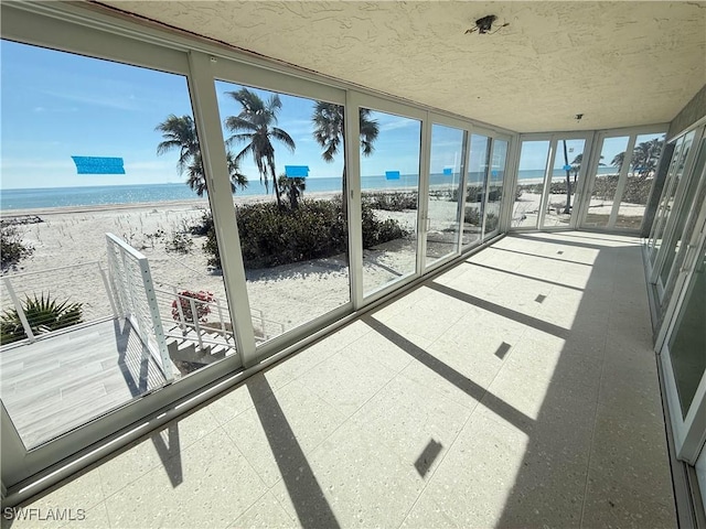 sunroom featuring a view of the beach and a water view