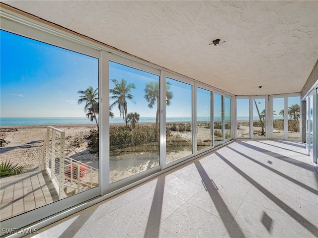 sunroom with a beach view and a water view