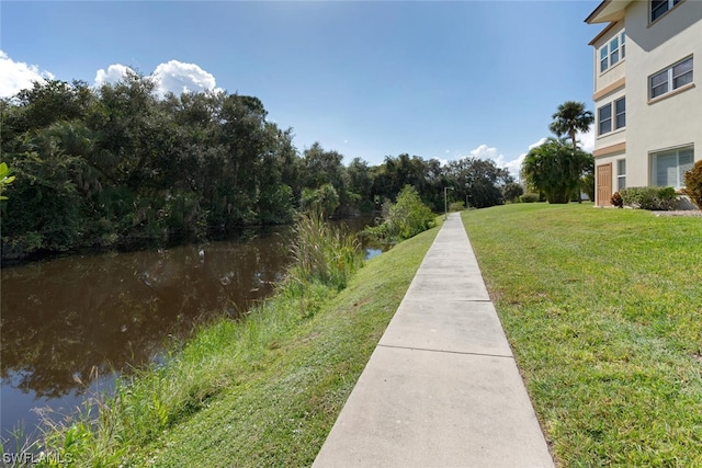 view of property's community with a lawn and a water view