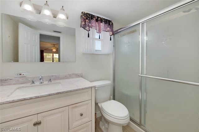 bathroom with vanity, toilet, a shower with door, and ceiling fan