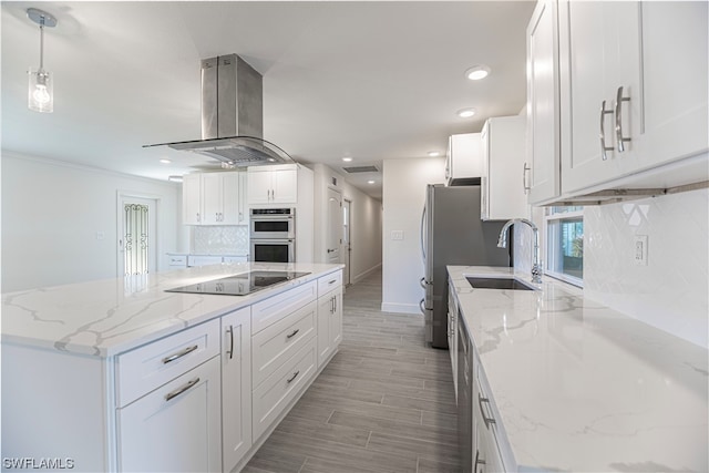 kitchen with light stone countertops, backsplash, stainless steel appliances, white cabinets, and island range hood