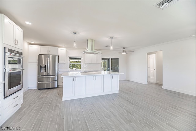 kitchen featuring ceiling fan, island exhaust hood, hanging light fixtures, white cabinets, and appliances with stainless steel finishes