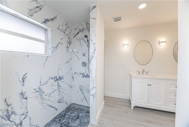 bathroom featuring tile flooring, vanity, and tiled shower