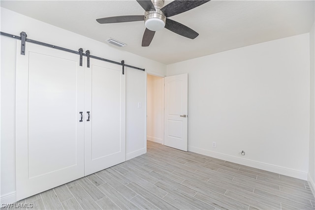 unfurnished bedroom featuring a barn door, a closet, and ceiling fan