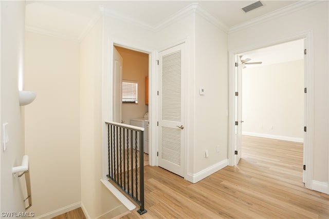 hallway with ornamental molding, light hardwood / wood-style flooring, and washer / dryer