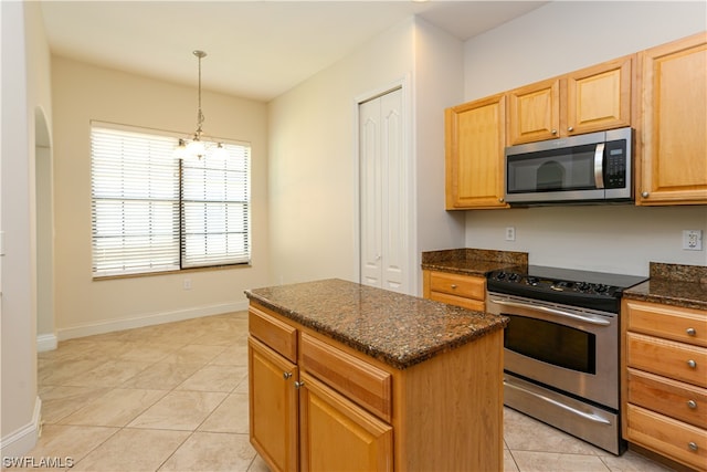 kitchen featuring light tile floors, appliances with stainless steel finishes, a chandelier, and dark stone countertops