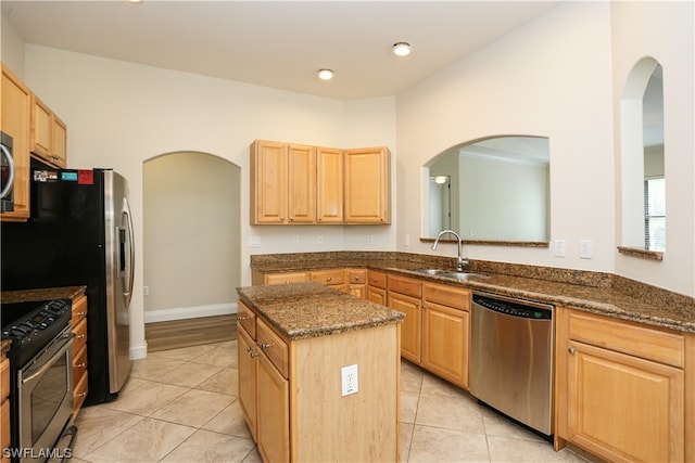 kitchen featuring sink, light tile floors, dark stone counters, a kitchen island, and stainless steel appliances