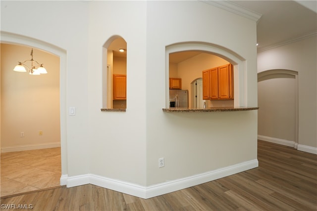 kitchen with dark stone countertops, hardwood / wood-style floors, a chandelier, and stainless steel fridge