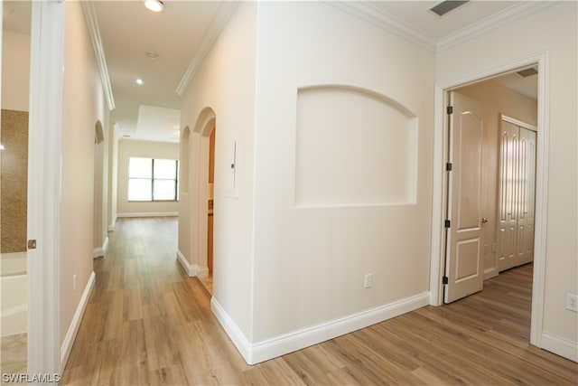 hallway with ornamental molding and light wood-type flooring