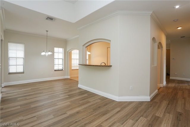 spare room featuring an inviting chandelier, crown molding, and hardwood / wood-style flooring