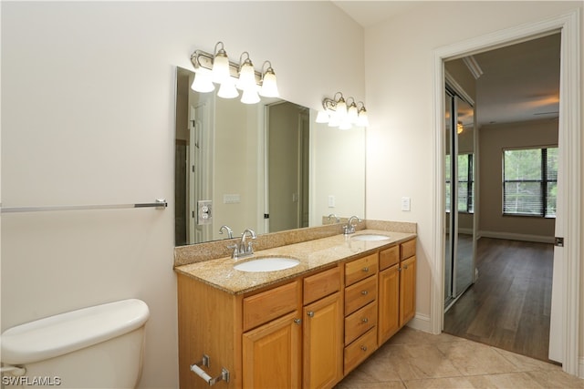 bathroom with double sink vanity, toilet, ornamental molding, and tile floors