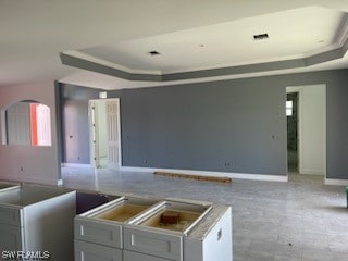 interior space with a tray ceiling and light tile floors