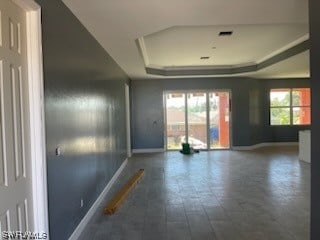 unfurnished room featuring dark tile flooring and a tray ceiling