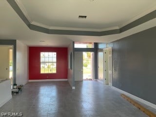 tiled spare room featuring crown molding and a tray ceiling