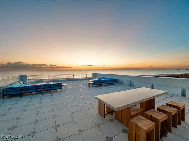 patio terrace at dusk featuring a water view and outdoor lounge area