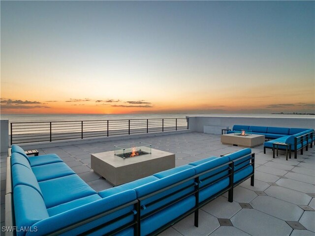 patio terrace at dusk with a water view and an outdoor living space with a fire pit