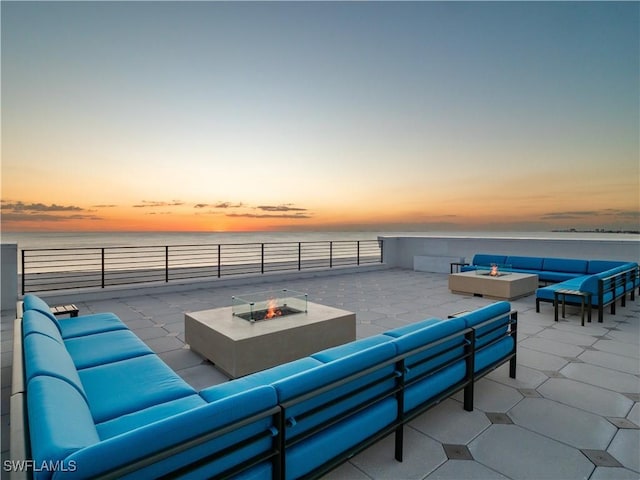 patio terrace at dusk featuring an outdoor living space with a fire pit and a water view