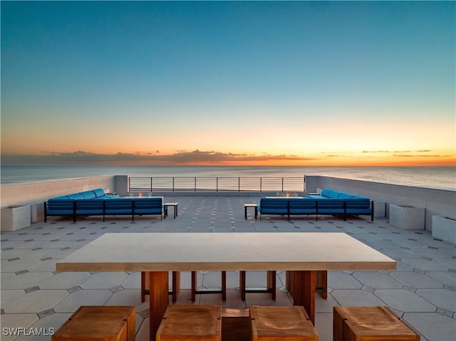 patio terrace at dusk with a water view and an outdoor living space