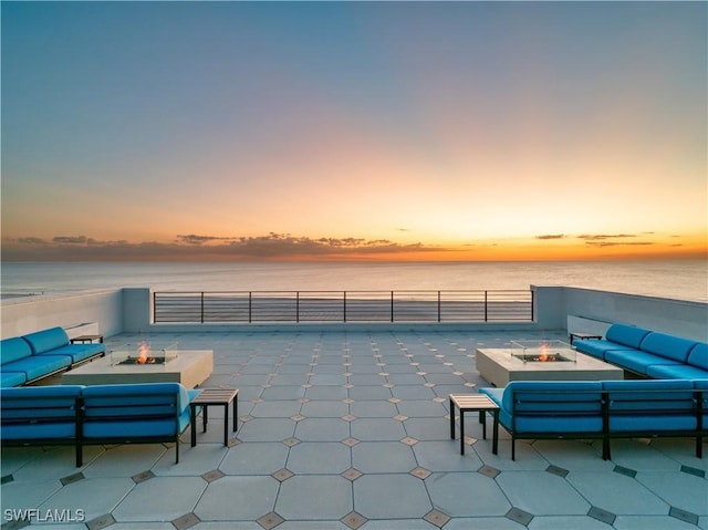 patio terrace at dusk featuring an outdoor living space with a fire pit and a water view