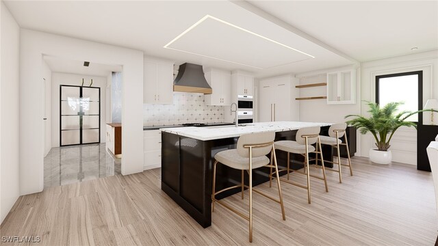 kitchen with tasteful backsplash, white cabinetry, a kitchen breakfast bar, a center island, and custom range hood