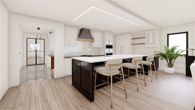 kitchen with decorative backsplash, a breakfast bar, a kitchen island, custom range hood, and white cabinets