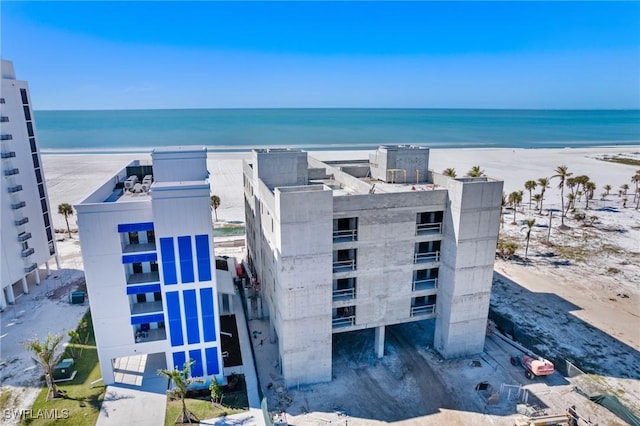 view of building exterior featuring a water view and a beach view