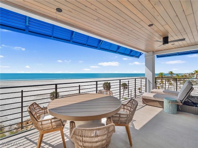 view of patio featuring a beach view, ceiling fan, a balcony, and a water view