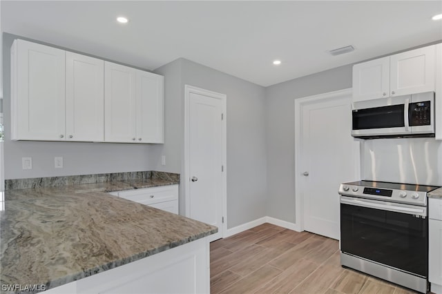 kitchen featuring dark stone countertops, white cabinetry, and appliances with stainless steel finishes