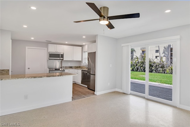 kitchen with white cabinetry, sink, ceiling fan, stainless steel appliances, and light stone counters