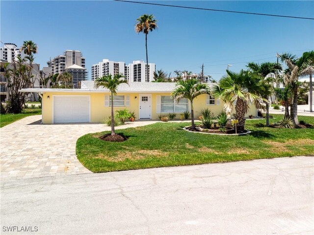 2 Fairview Blvd, Fort Myers Beach, FL 33931 - view of front facade with decorative driveway, a front lawn, an attached garage, and stucco siding