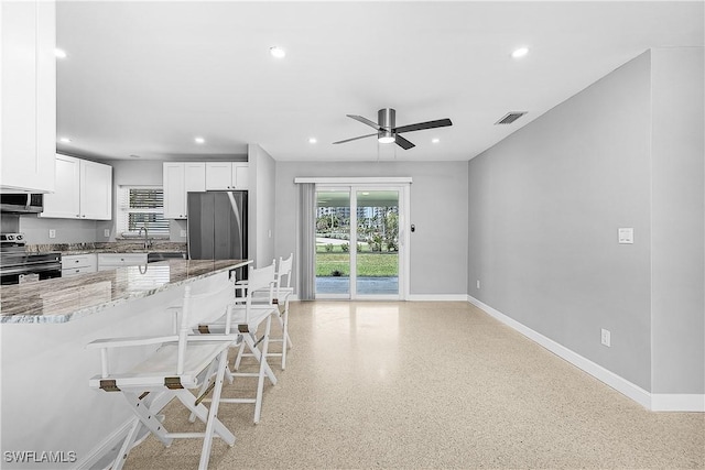 2 Fairview Blvd, Fort Myers Beach, FL 33931 - kitchen featuring stainless steel appliances, a kitchen breakfast bar, light stone counters, baseboards, and ceiling fan