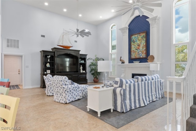 living room with light tile floors, ceiling fan, and a towering ceiling