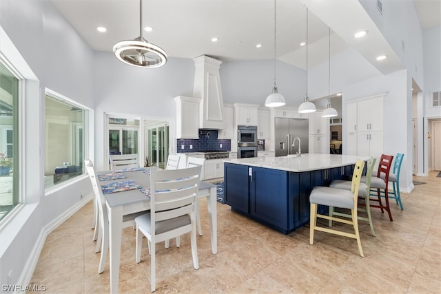 kitchen with stainless steel appliances, a kitchen bar, backsplash, hanging light fixtures, and a kitchen island with sink