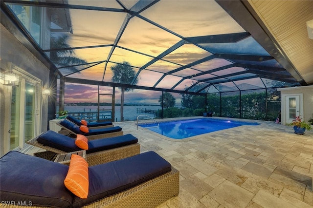 pool at dusk featuring glass enclosure and a patio