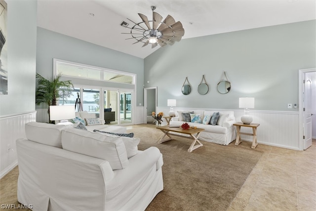 living room featuring light tile floors, ceiling fan, and a towering ceiling