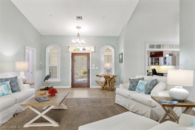 carpeted living room with a chandelier and high vaulted ceiling