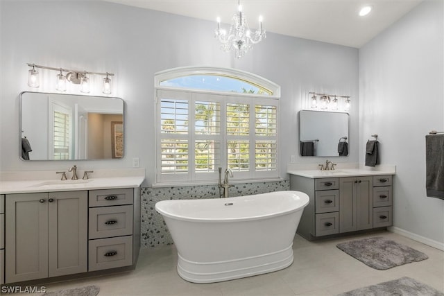 bathroom featuring a notable chandelier, dual bowl vanity, a bath, and tile flooring