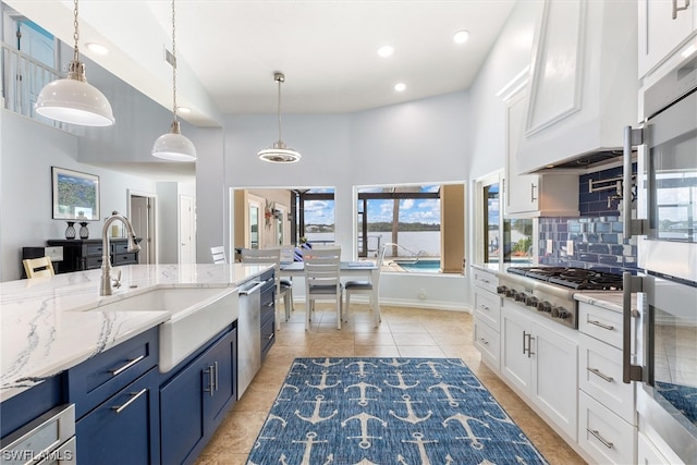 kitchen with light tile floors, light stone countertops, high vaulted ceiling, tasteful backsplash, and decorative light fixtures